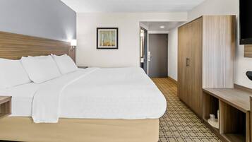 A hotel room with a large bed, a wooden wardrobe, a television, and a framed picture on the wall.