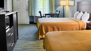 A hotel room with two beds, a desk, a chair, a TV, and a lamp. - Quality Inn Thornburg (Woodford)