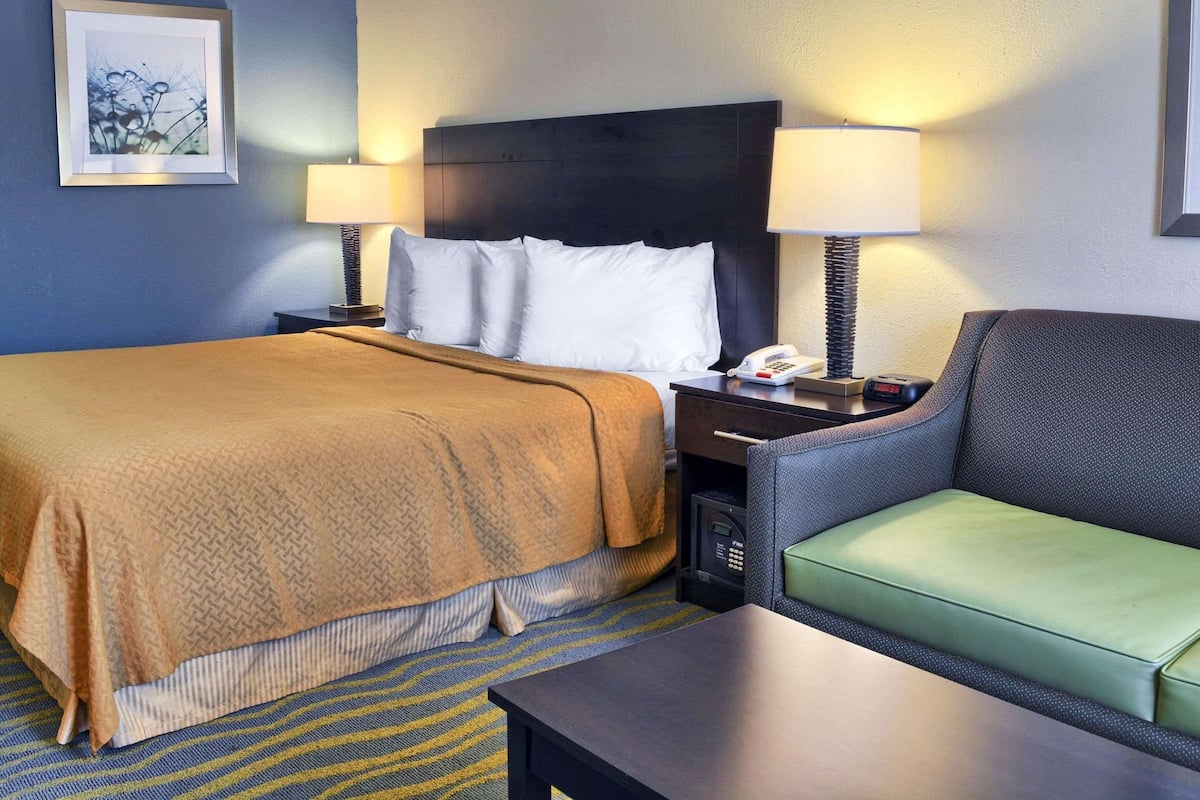 A hotel room with a bed, two bedside tables, a chair, and a desk.