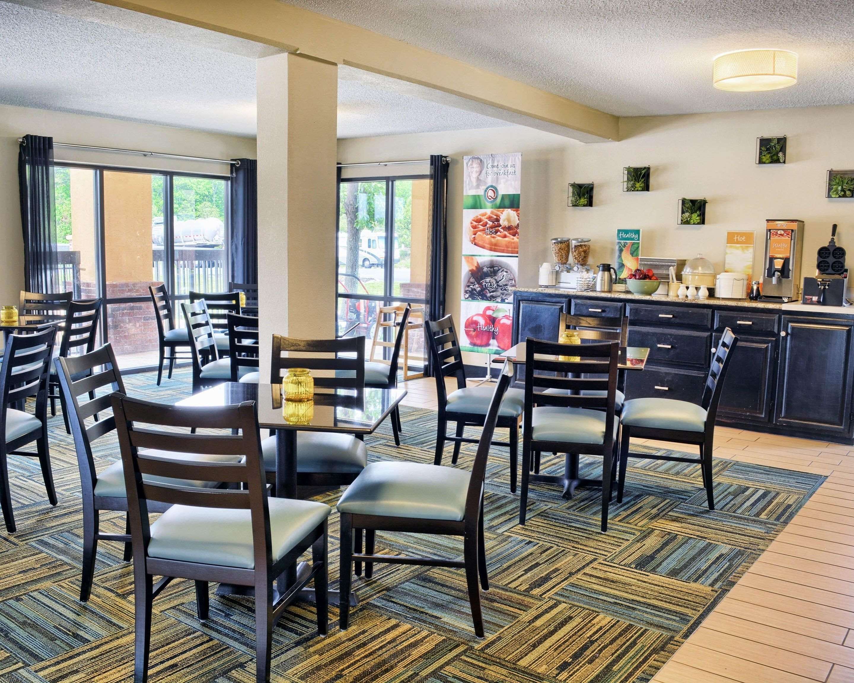 A dining area with tables and chairs, a kitchen area with appliances, and a view of the outdoors.