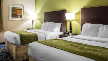 Habitación de hotel con dos camas, paredes verdes y alfombra estampada.
