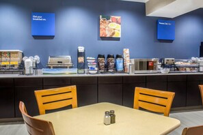 A breakfast bar with coffee machines, food containers, and seating. - Econo Lodge Ankeny - Des Moines (Ankeny)