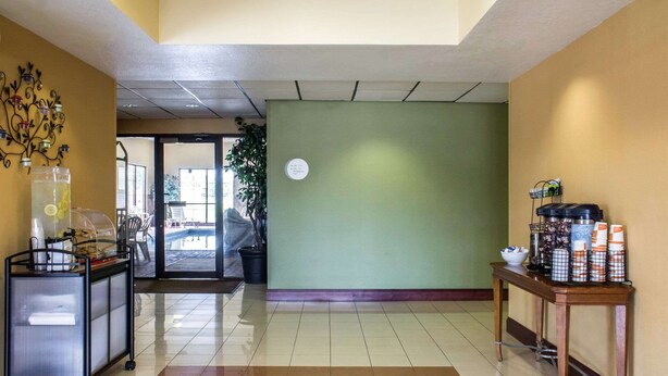 A hotel lobby with a tiled floor, a reception desk, a green wall, and a door leading to a pool area. - Econo Lodge Ankeny - Des Moines (Ankeny)