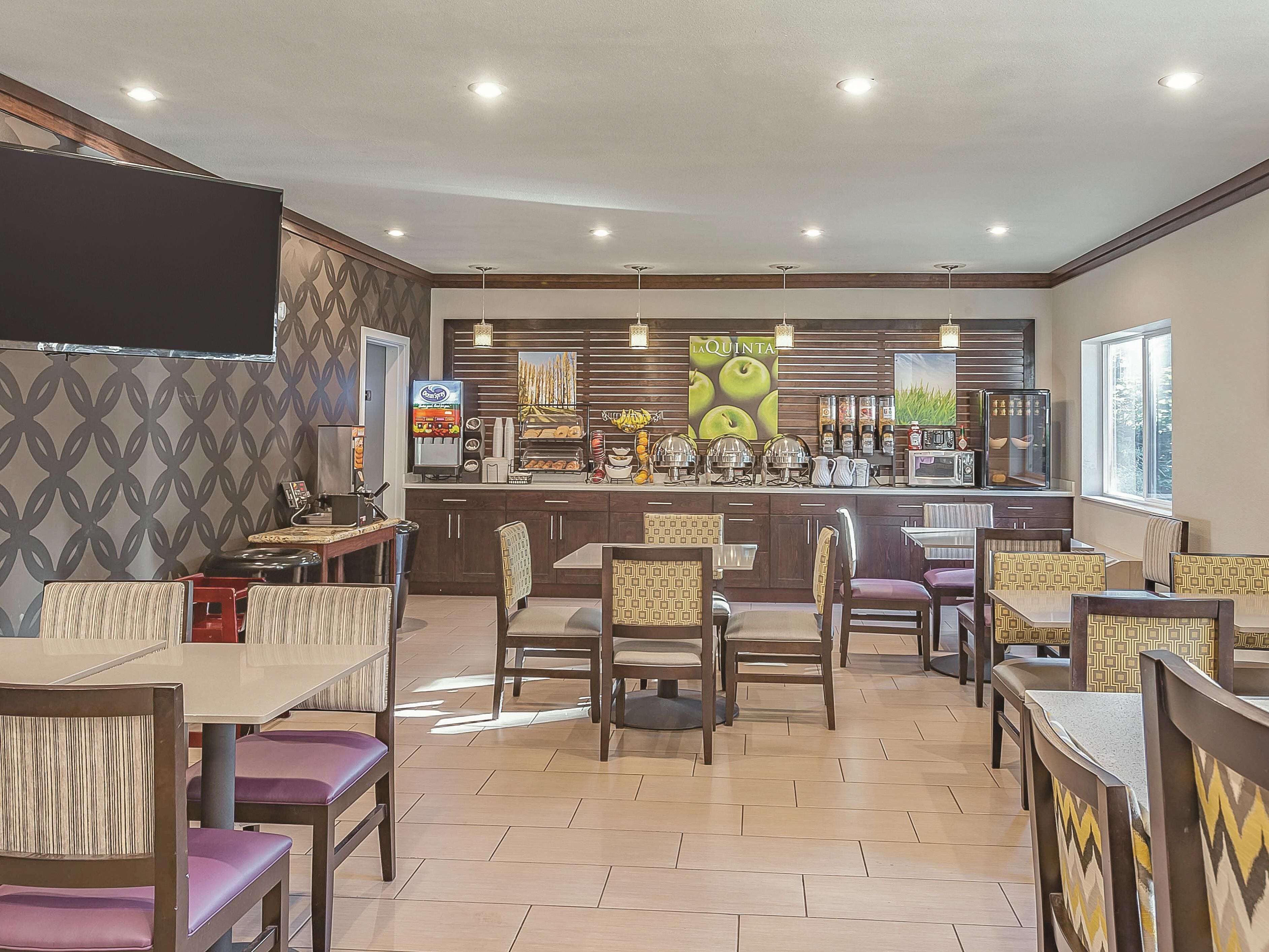 A restaurant with a bar area, seating, and a TV screen.