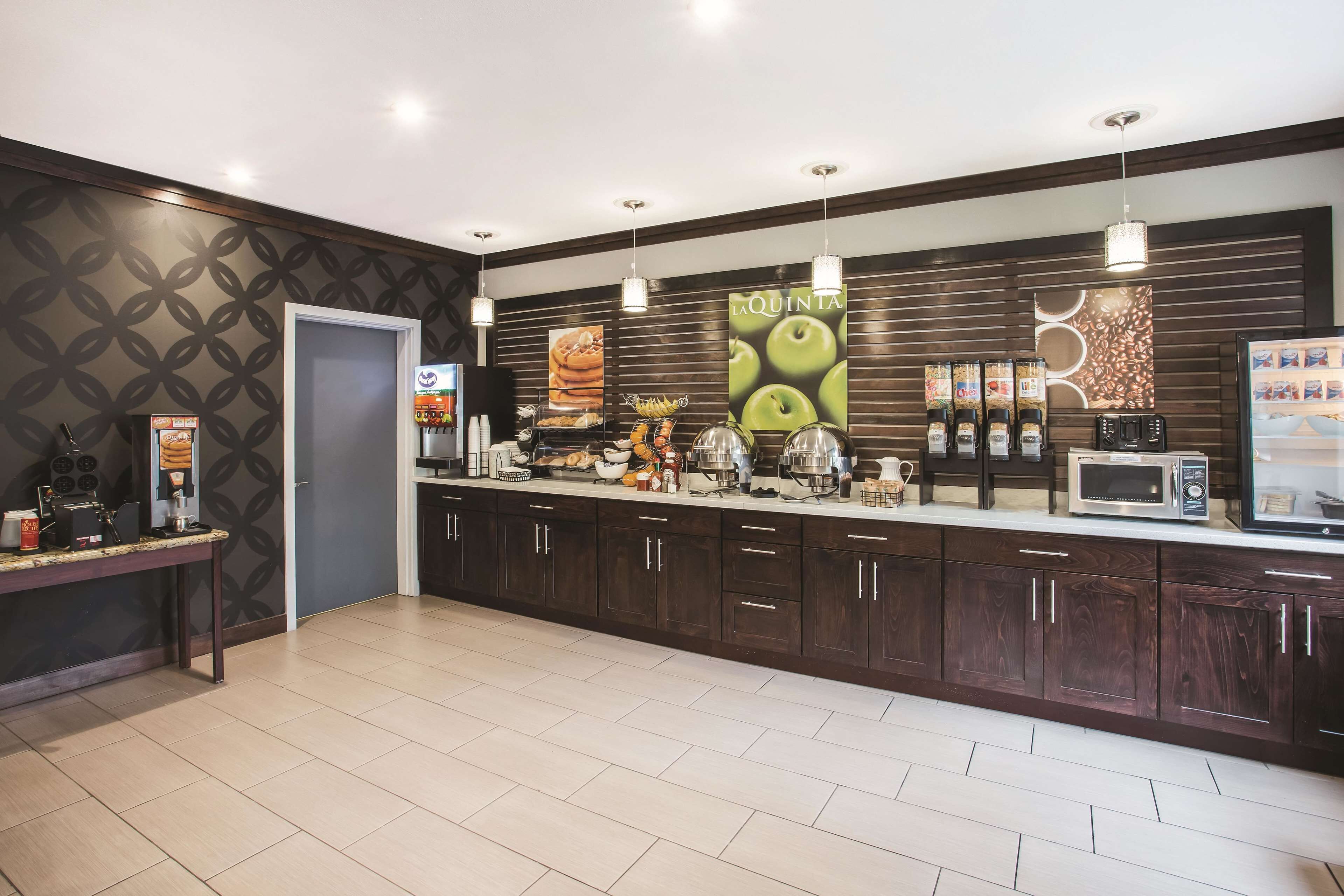 A modern kitchen with dark wood cabinets, a microwave, and a coffee machine.