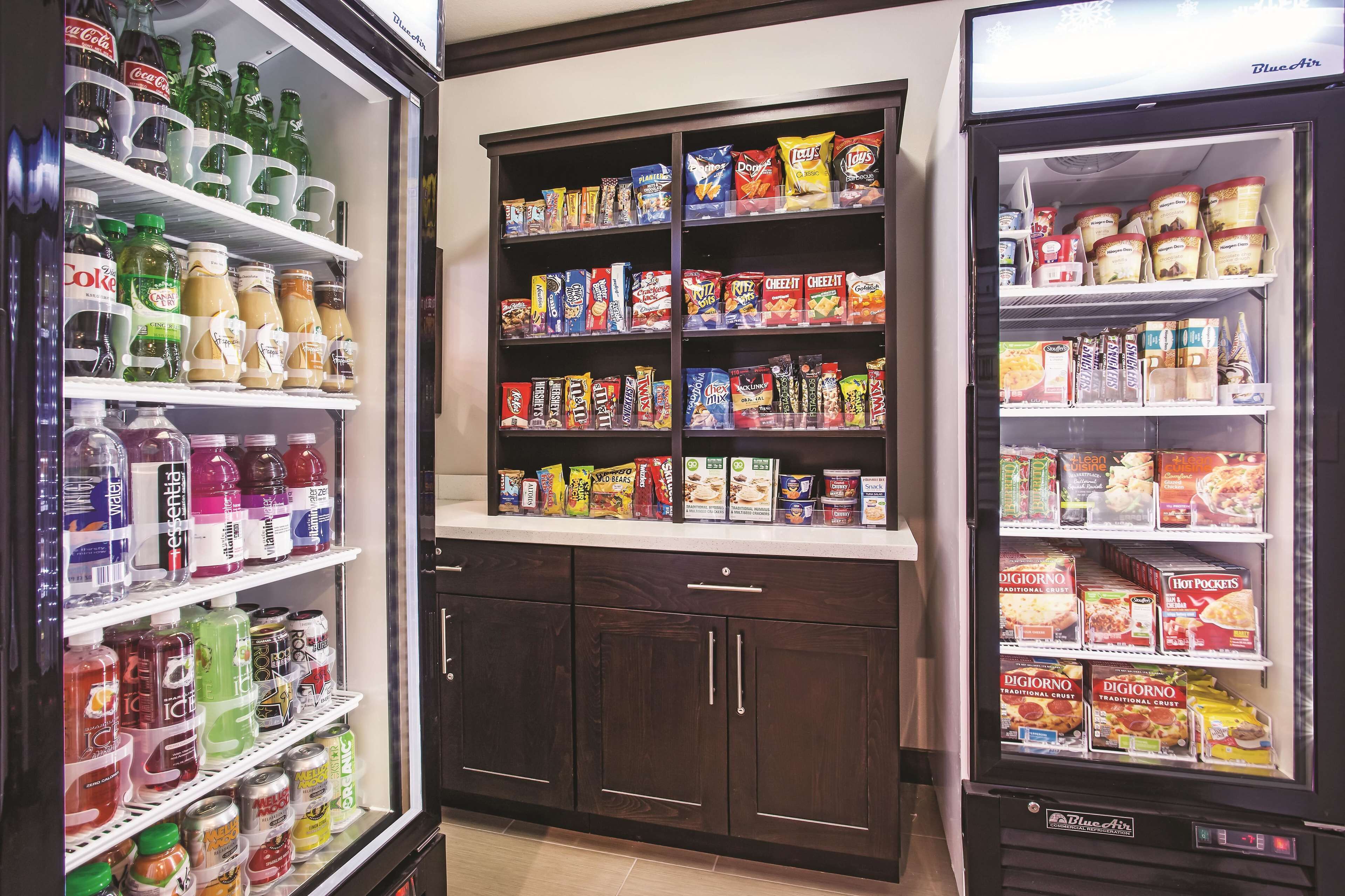 Máquina expendedora llena de aperitivos y bebidas, incluyendo refrescos, papas fritas y bebidas energéticas.