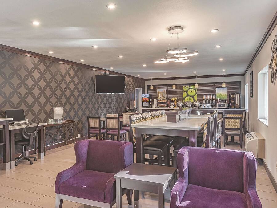 Un café moderne avec des chaises violettes, un coin bar et un téléviseur à écran plat fixé au mur.