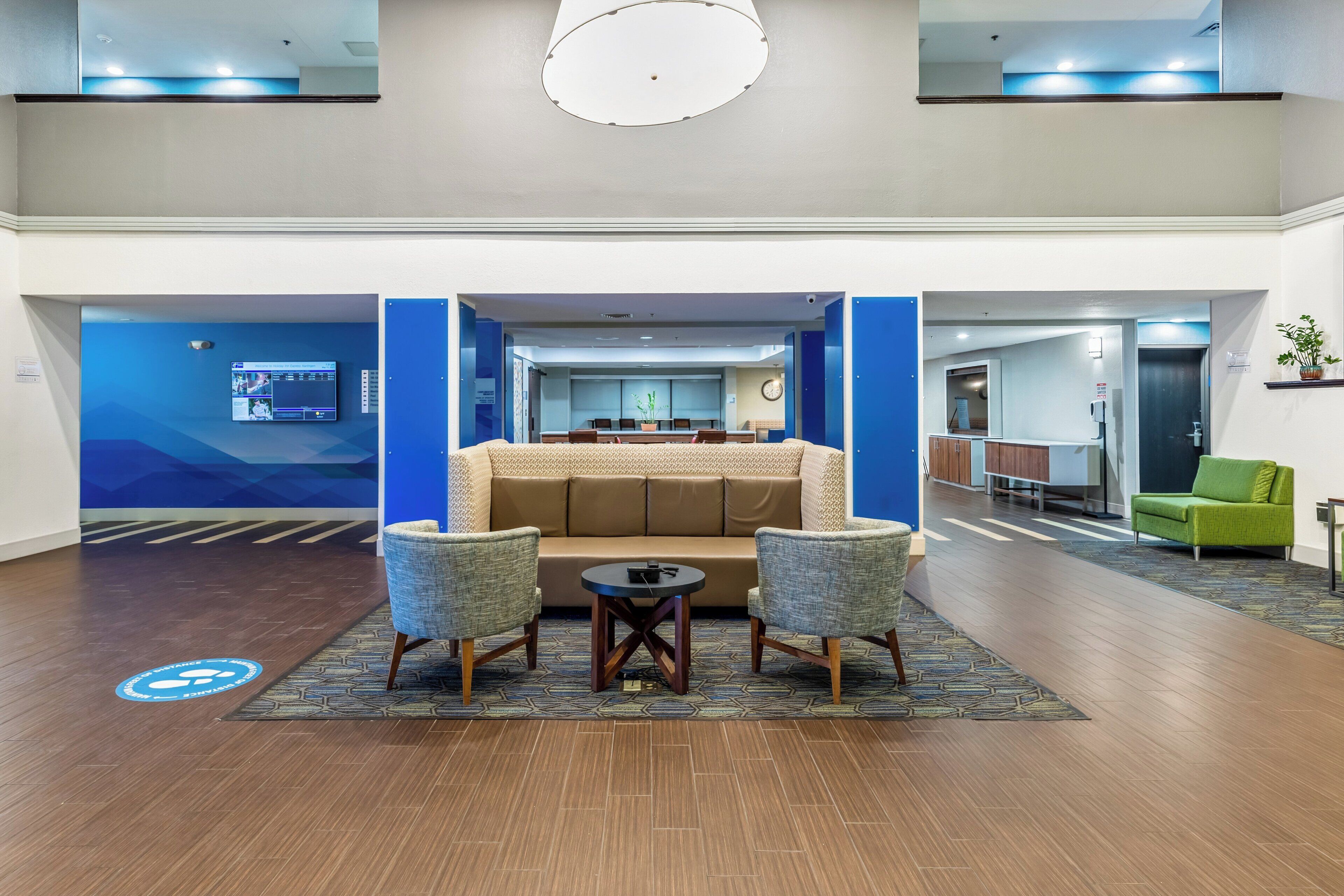 Um hall de entrada com sofá, duas poltronas, mesa de centro e balcão de recepção.