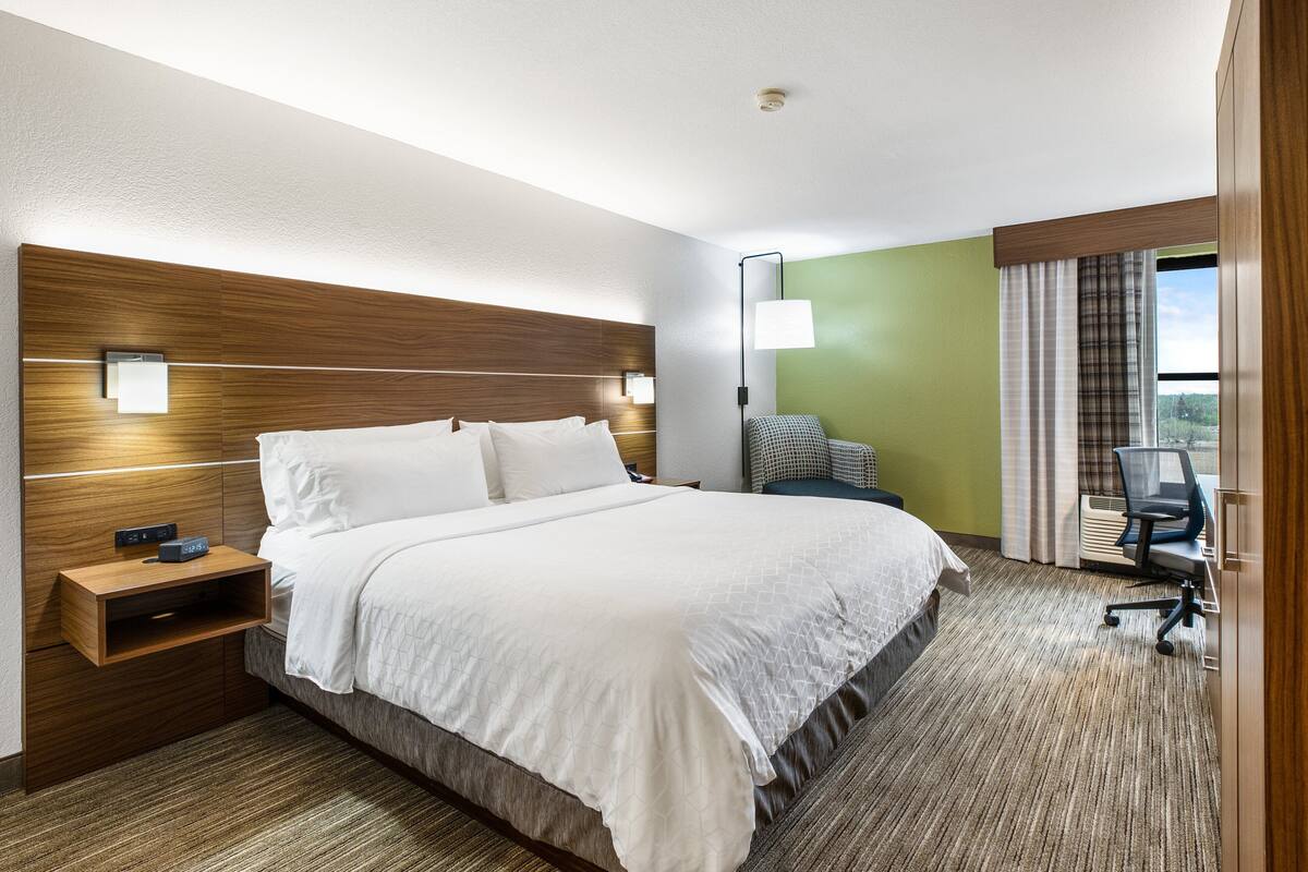 A hotel room with a large bed, a desk, and a chair.