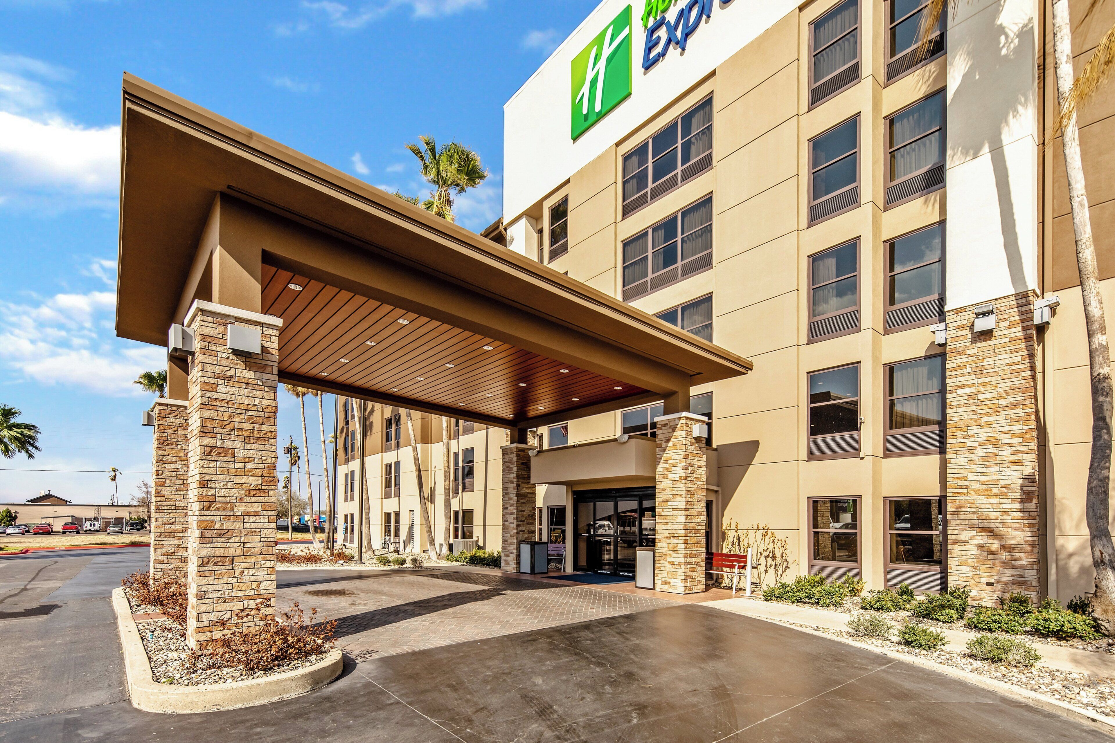 A hotel with a covered entrance, stone pillars, and a clear sky.