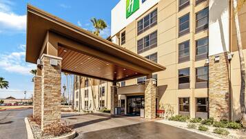 A hotel with a covered entrance, stone pillars, and a clear sky.