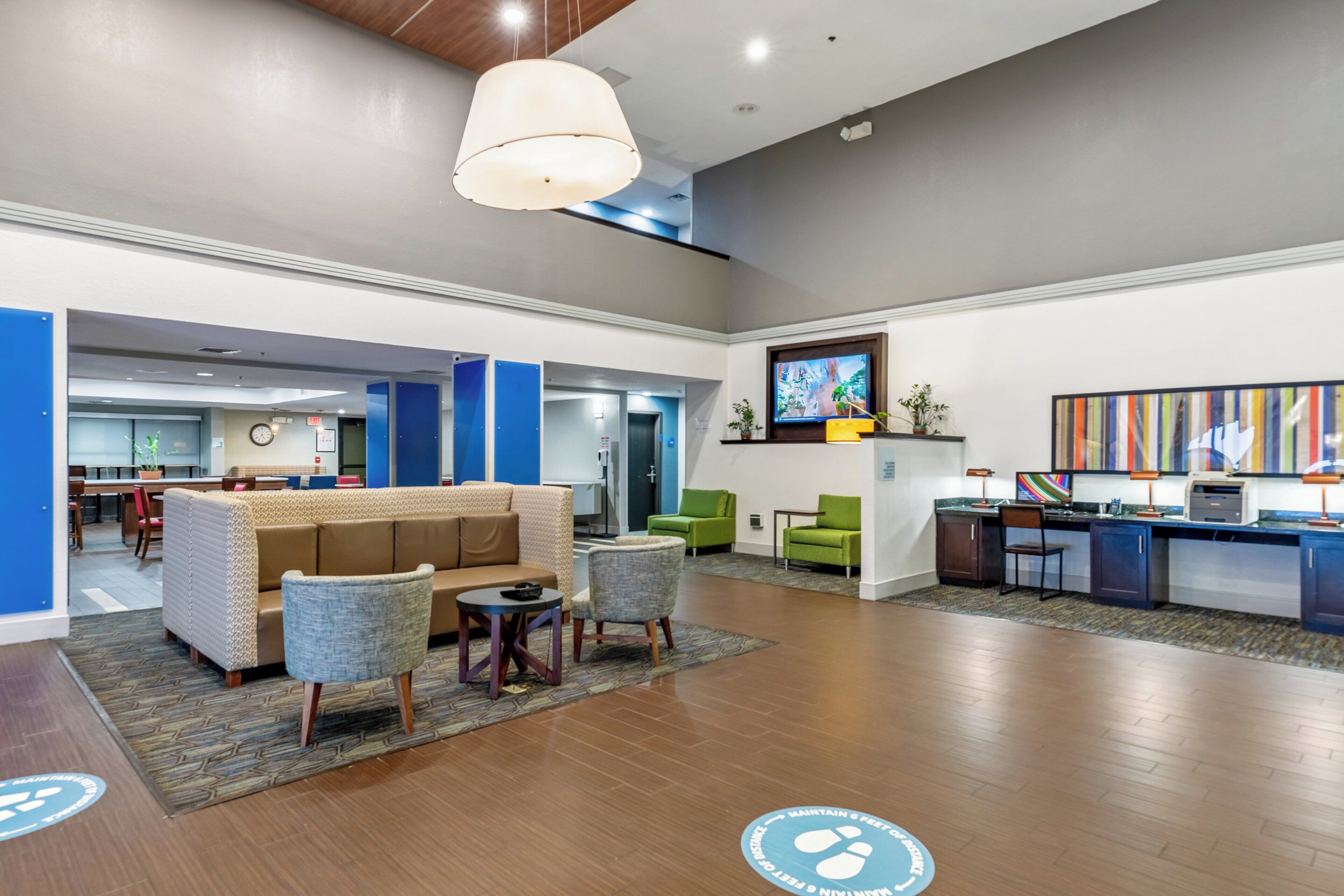 A lobby area with a sofa, chairs, a small table, a reception desk, and a television.