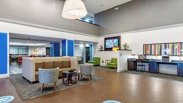 A lobby area with a sofa, chairs, a small table, a reception desk, and a television.