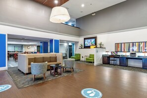 A lobby area with a sofa, chairs, a small table, a reception desk, and a television.