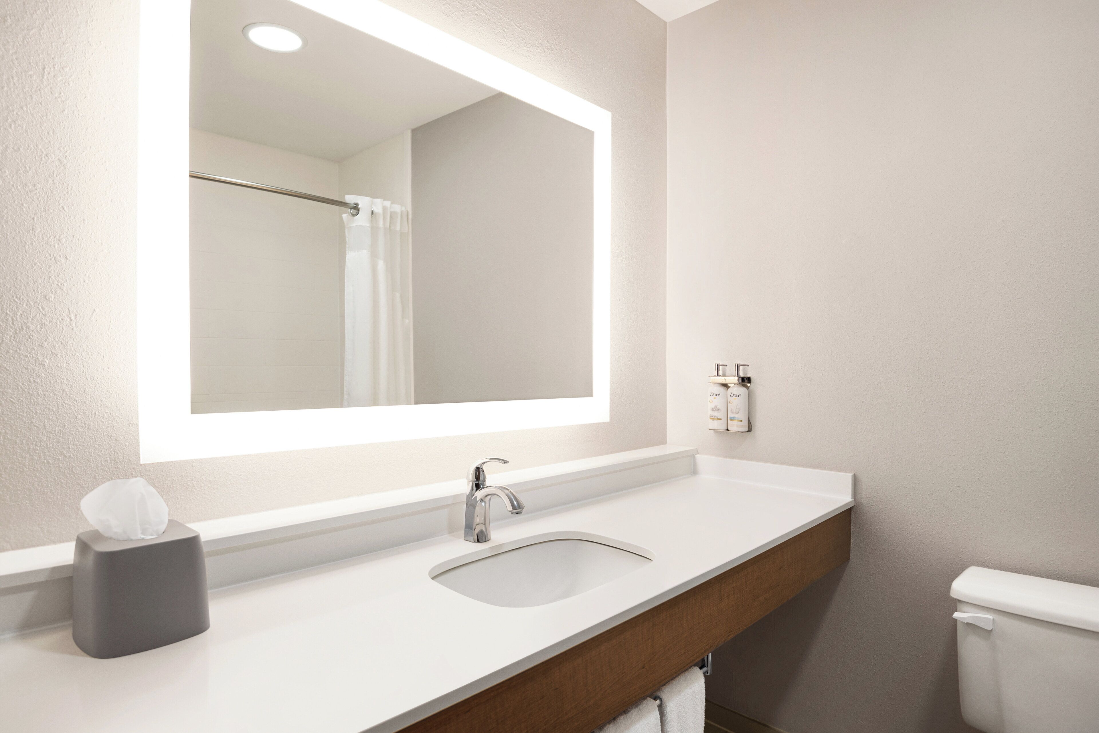 A bathroom with a large mirror, a sink, and a toilet.