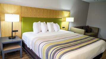 Ein Hotelzimmer mit einem Bett, zwei Nachttischlampen, einem kleinen Tisch und einem Sofa.