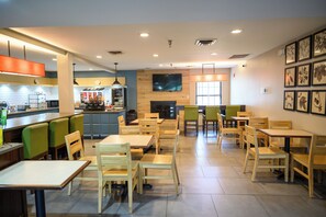 A restaurant with multiple dining tables and chairs, a kitchen area, and a television mounted on the wall. - Country Inn & Suites by Radisson, Greenfield, IN (Greenfield)