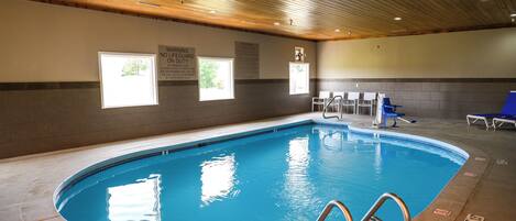 An indoor swimming pool with a wooden ceiling, clear signage, and a tiled floor.