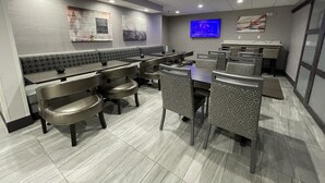 Restaurante moderno com assentos em cabines, mesas altas e cadeiras estampadas.