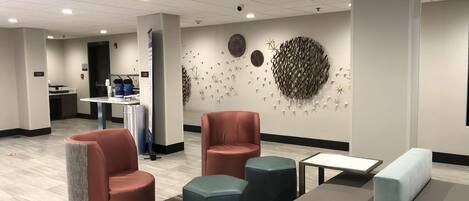 En moderne lobby med siddeområder, en receptionsdisk og dekorativ vægkunst.