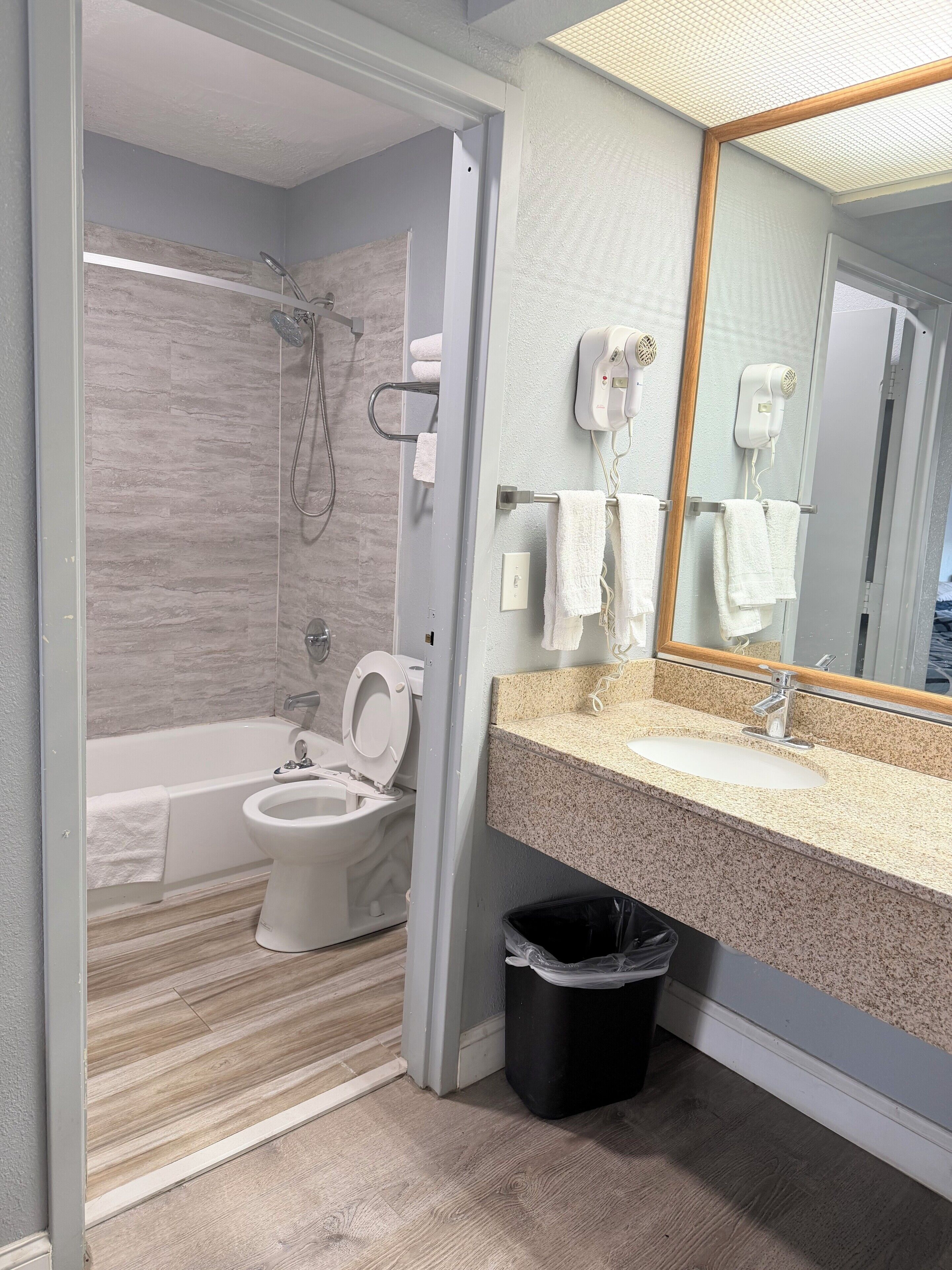 Une salle de bain moderne équipée d’une douche, de toilettes et d’un lavabo, ainsi que d’une poubelle et de serviettes.
