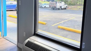Ein Zimmer mit einem großen Fenster, einer Wand-Klimaanlage und einer Tür, die nach draußen führt.