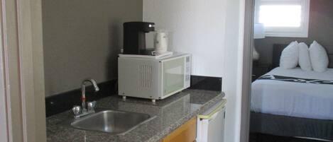 Eine kleine Küche mit Spüle, Kaffeemaschine und Mikrowelle.