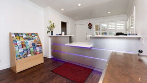 A reception area with a wooden display of postcards, a red rug, and a counter with a blue light strip.