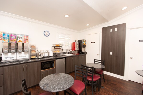 A compact kitchen with a coffee station, a microwave, and a sink.