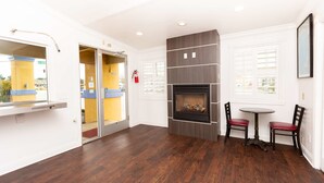 A modern interior with a fireplace, a dining area with two chairs, and a view through a glass door.