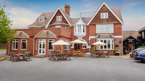 A large brick building with a traditional architectural style, featuring a prominent entrance with a sign reading "Hickstead Hotel Reception." - The Hickstead Hotel (Haywards Heath)