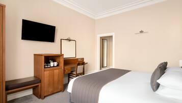 A hotel room with a bed, a desk, a chair, a television, and a wardrobe.