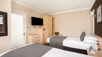 A hotel room with two beds, a TV, a wardrobe, and a desk.