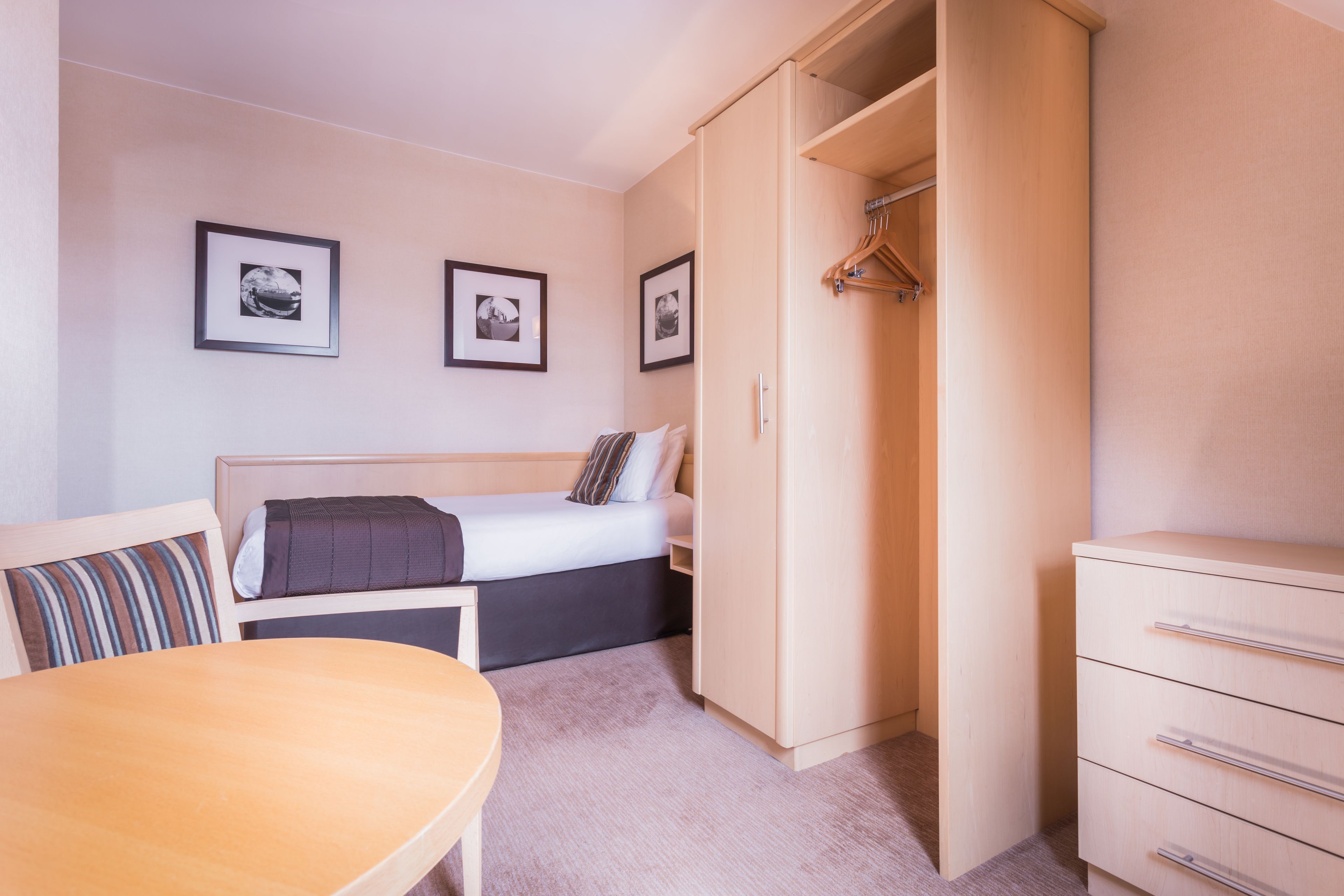 A bedroom with a bed, bedside table, wardrobe, and a small table with chairs.