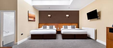 Habitación de hotel con tragaluz, dos camas, televisión y vista al exterior.