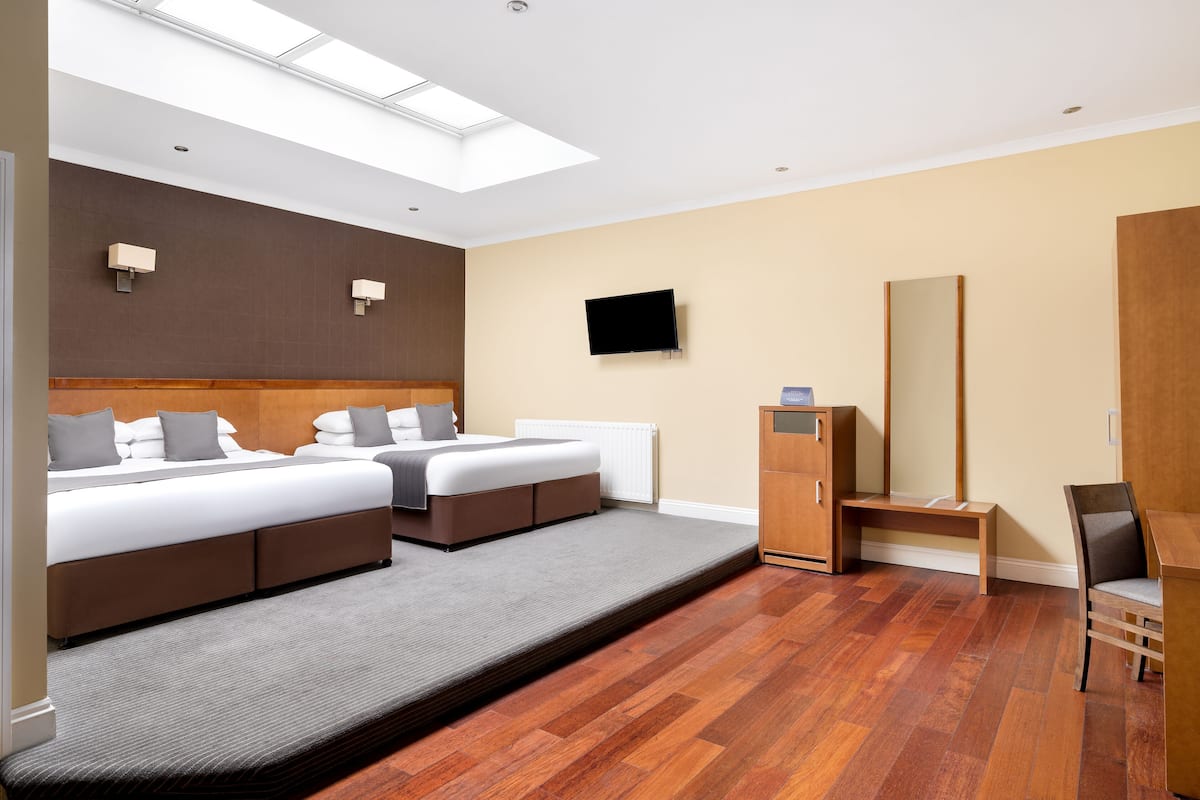 Een hotelkamer met een groot bed, een bureau, een stoel, een televisie en een dakraam.