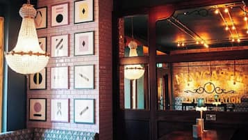 A cozy bar area with a brick wall adorned with framed pictures, a hanging chandelier, and a counter with a sign reading "Newcastle Central Station".
