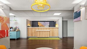 A reception area with a wooden counter, a green carpet, and a yellow light fixture.
