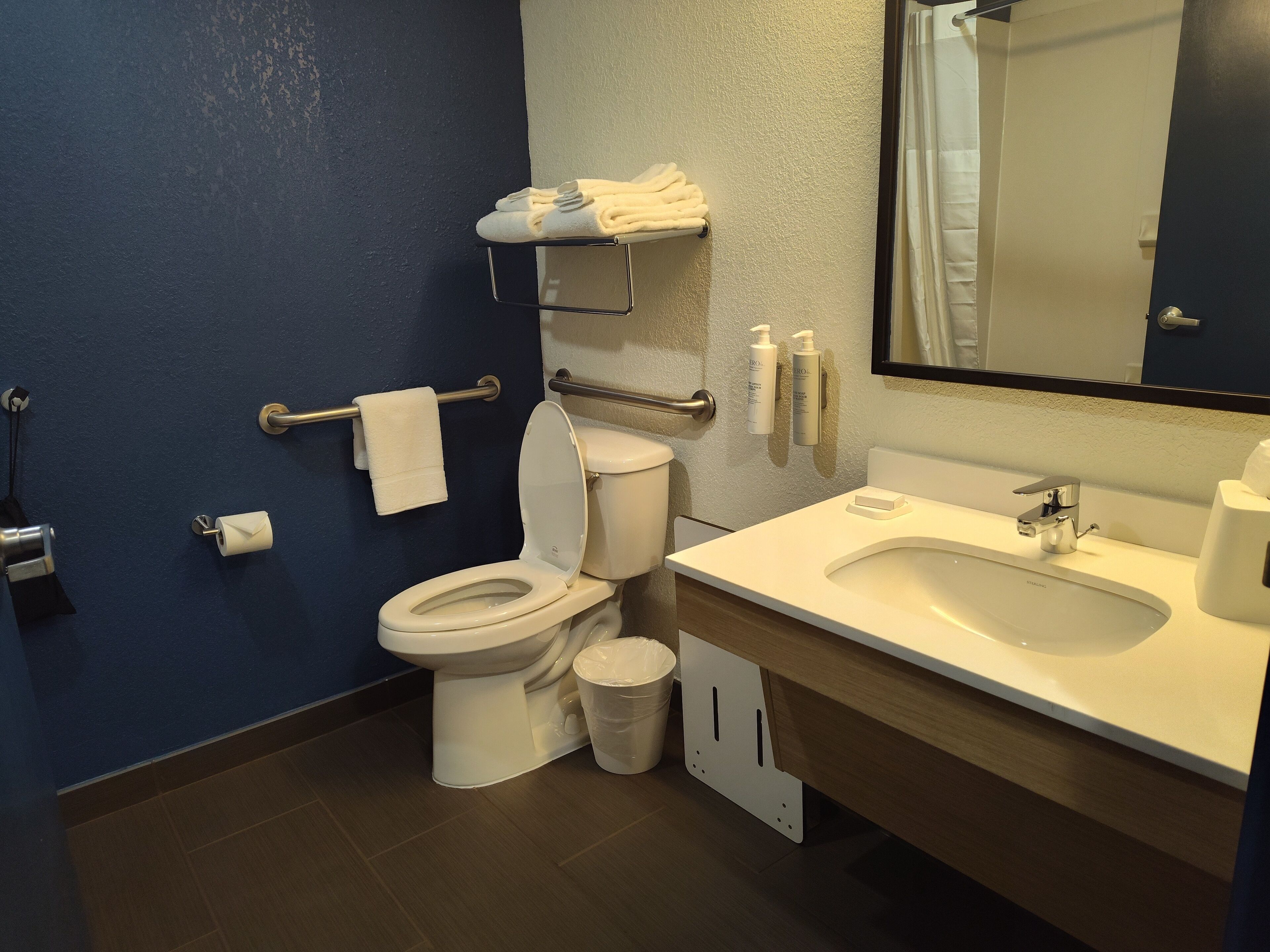 A modern bathroom with a toilet, sink, and mirror.