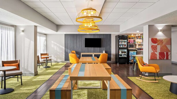 A modern meeting room with a wooden table, orange chairs, and a large screen.