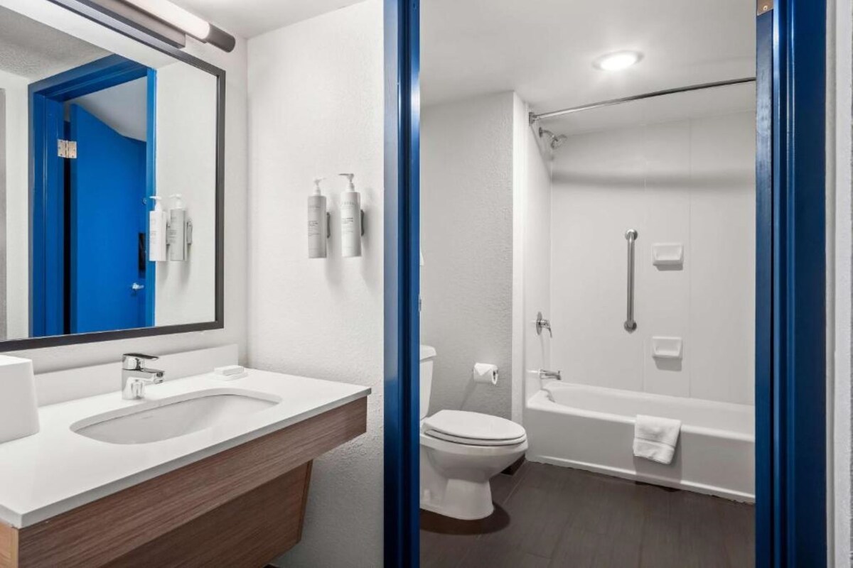 A bathroom with a white sink, mirror, toilet, and bathtub.