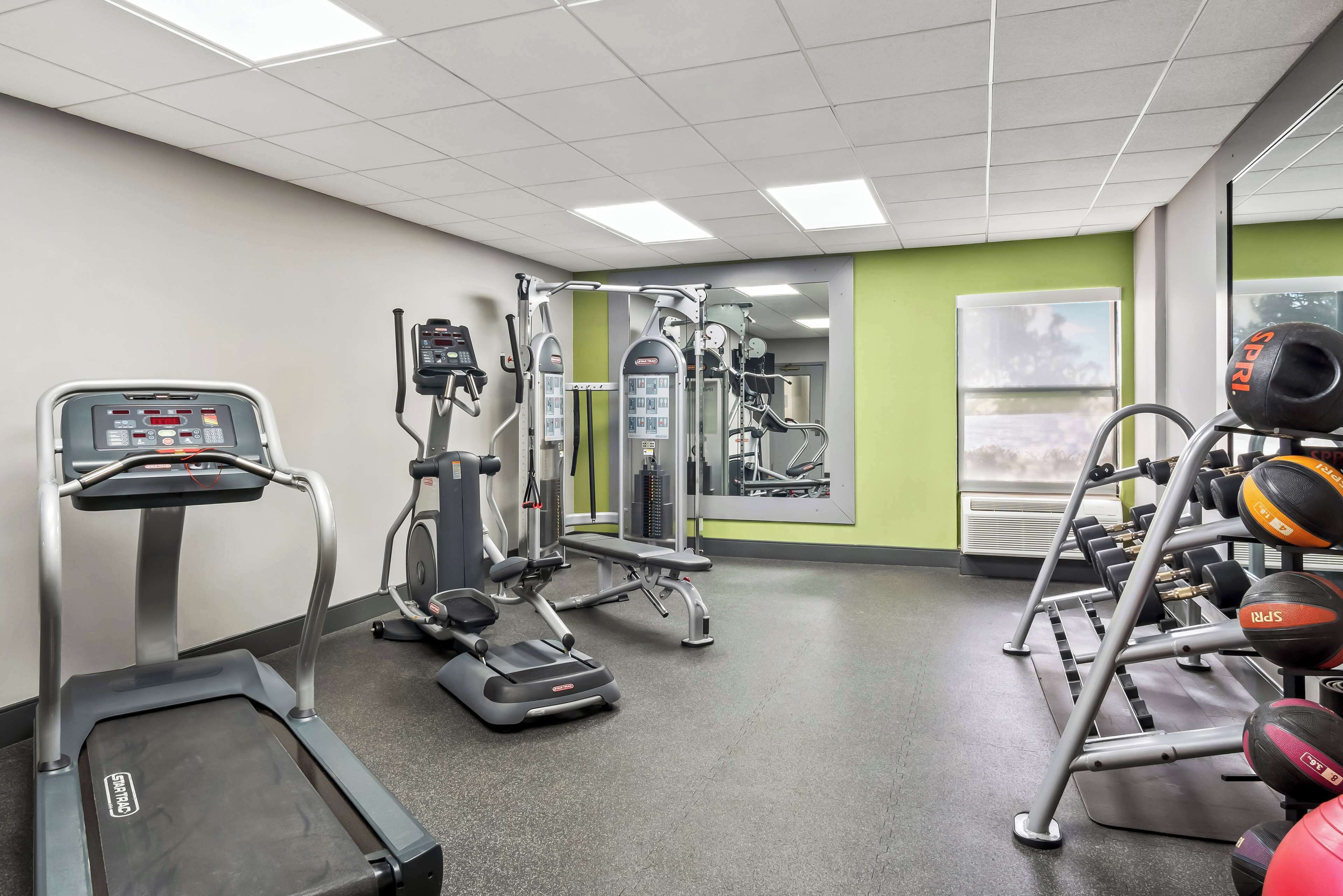 Un gimnasio con cintas de correr, elípticas y equipo de levantamiento de pesas.