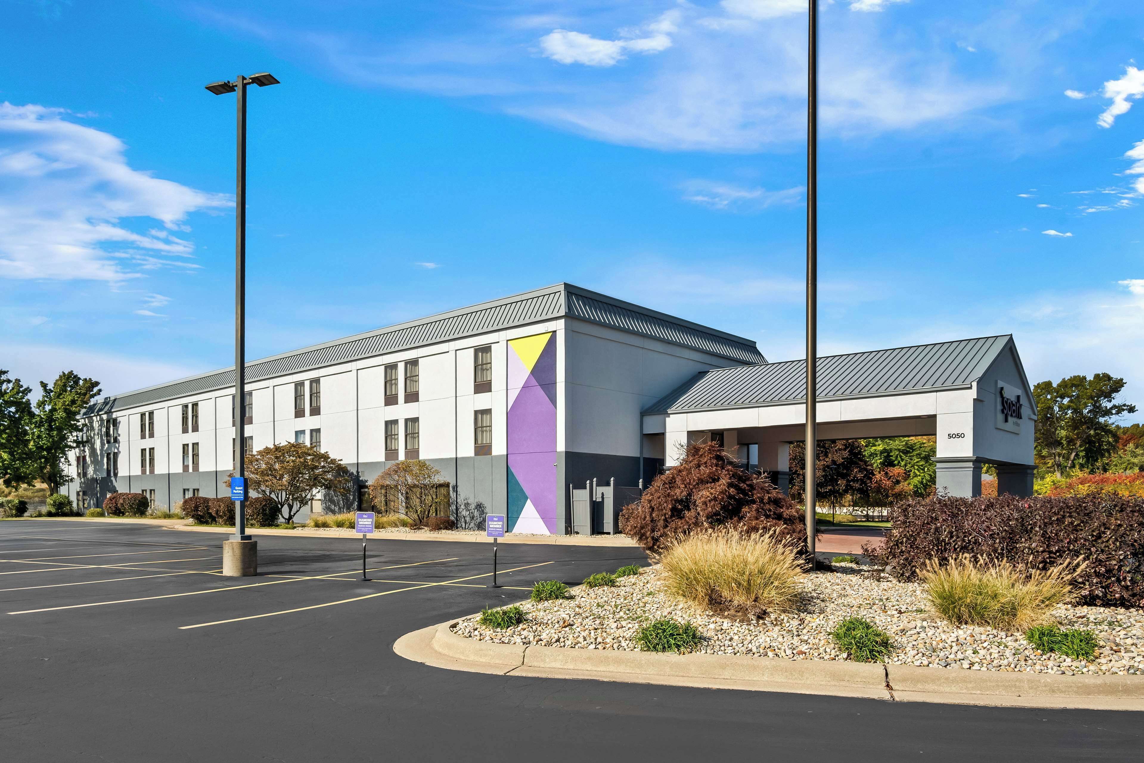 A modern building with a parking lot and a covered entrance.