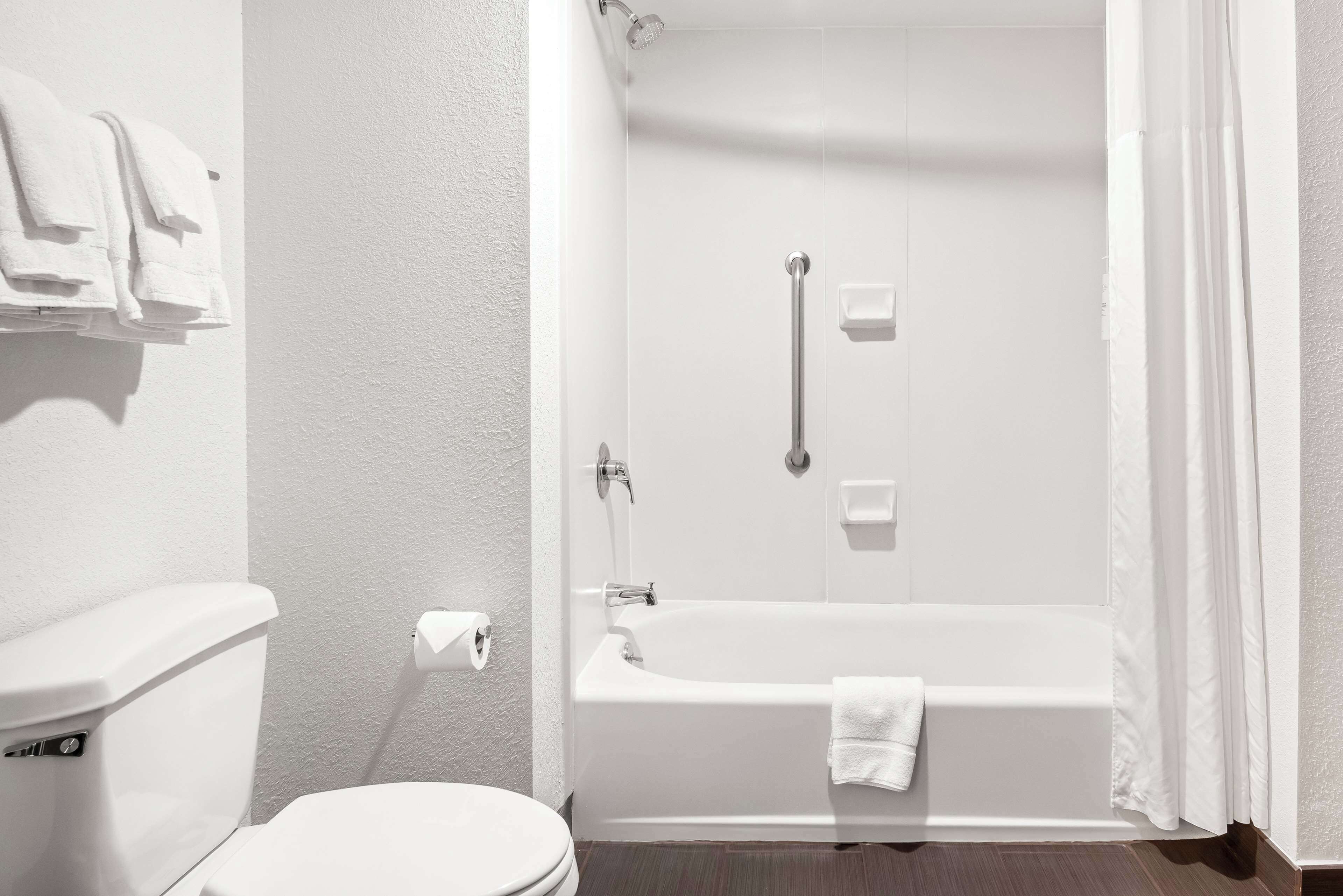 Un bagno con il water bianco, una vasca da bagno con un asciugamano e una zona doccia.