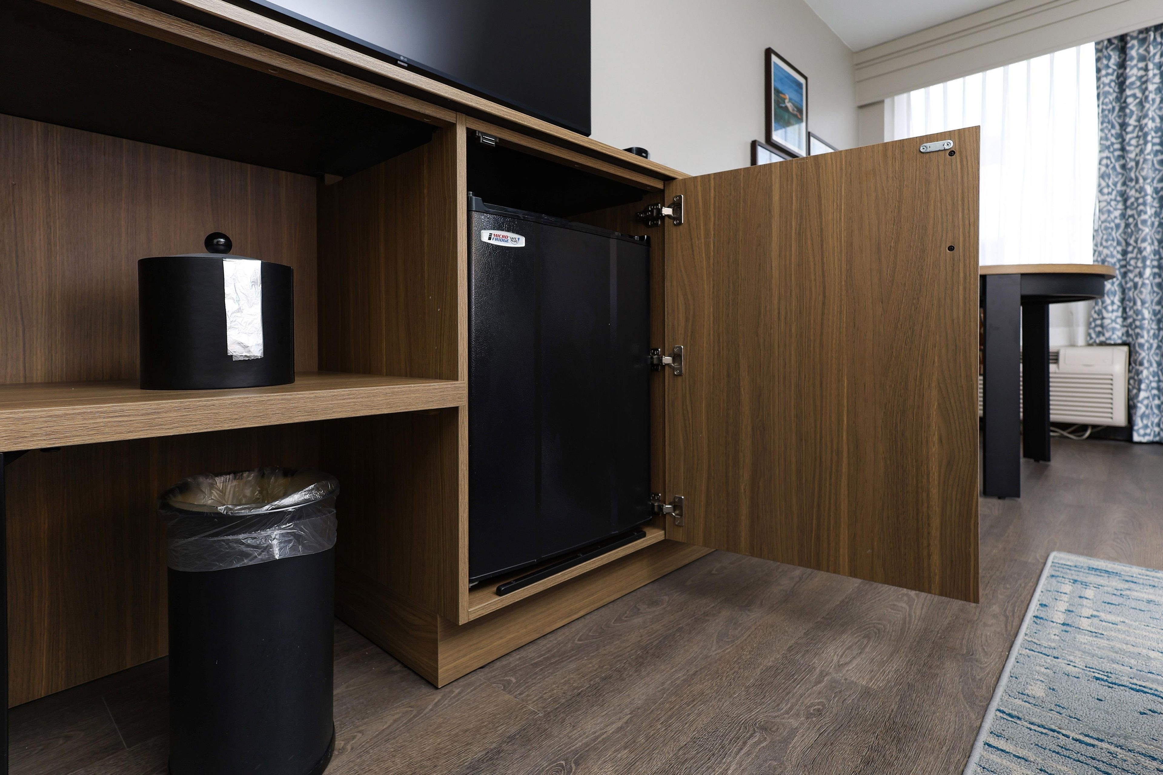 Una cocina compacta con refrigerador integrado, un cesto de basura y una repisa de madera.