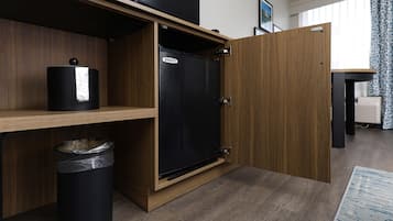 Una cocina compacta con refrigerador integrado, un cesto de basura y una repisa de madera.