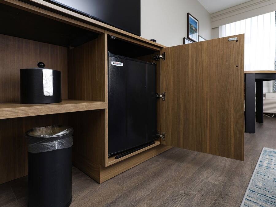 Una cocina compacta con refrigerador integrado, un cesto de basura y una repisa de madera.