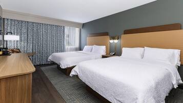 Une chambre d’hôtel avec deux lits, un bureau, un téléphone et une table de chevet.