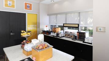 Ein Frühstücksbuffet mit Kaffeemaschine, Toaster und Obstauslage.