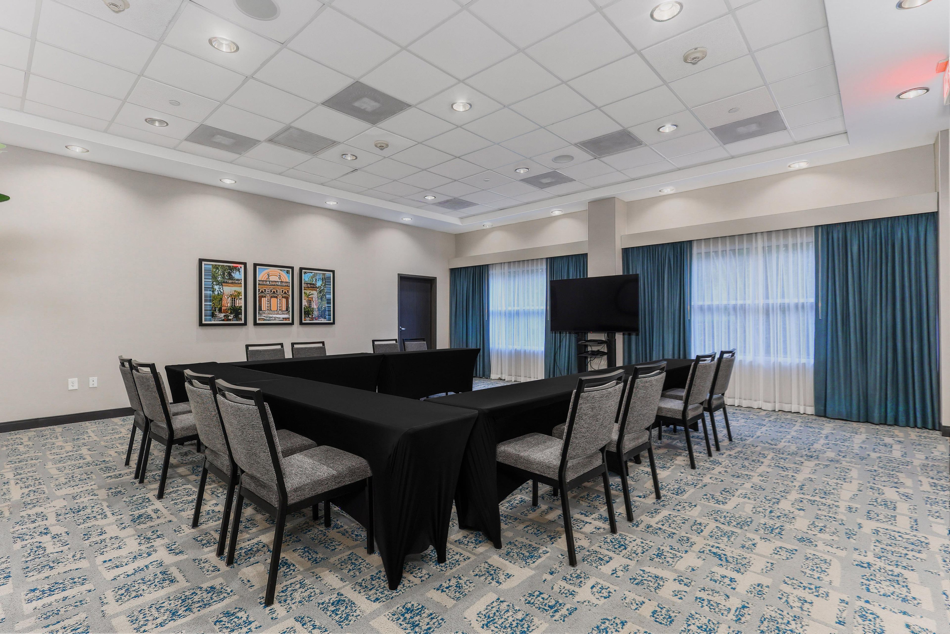 A conference room with a large table, chairs, a flat-screen TV, and artwork on the walls.